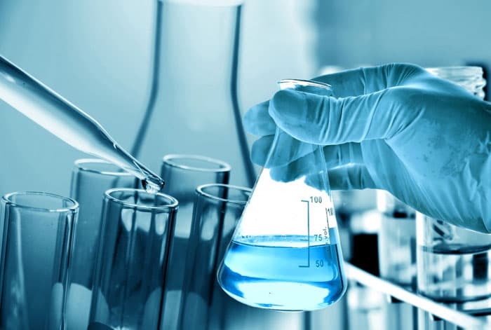 Pipetare într-un set de eprubete, lângă un balon Erlenmeyer cu probă de apă